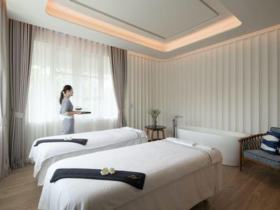 Moderní hotelový pokoj se dvěma postelemi, minimalistickým designem a servírkou s podnosem.