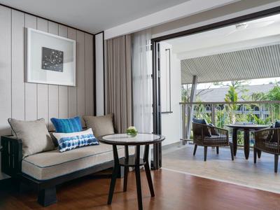 Moderní obývací pokoj s pohovkou, stolkem a zařízenou venkovní terasou pod střechou.