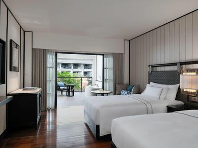 Moderní hotelový pokoj se dvěma dvoulůžky a terasou s výhledem do zahrady.