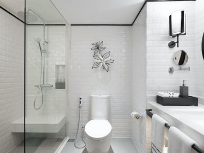 Moderní bílá koupelna se skleněným sprchovým koutem, toaletou a umyvadlem.