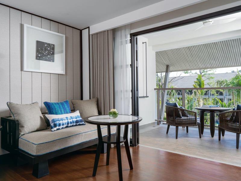 Moderní obývací pokoj s pohovkou, stolkem a zařízenou venkovní terasou pod střechou.