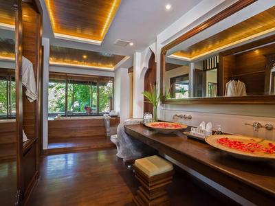 Salle de bain luxueuse avec détails en bois, deux vasques et grand miroir à côté d'une fenêtre avec vue sur le jardin.
