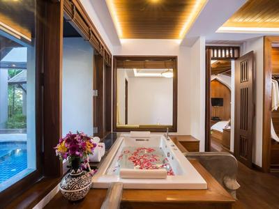 Baignoire luxueuse avec pétales de rose à côté d'une fenêtre donnant sur la piscine et décoration en bois.