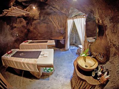 Salle de spa confortable dans une grotte naturelle avec tables de massage et accessoires bien-être.