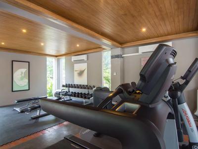 Moderner Fitnessraum mit Laufbändern, Gewichten und Holzbalkendecke in einem Hotel.