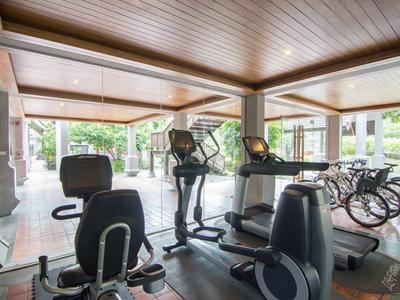 Moderner Fitnessraum mit Trainingsgeräten und großer Fensterfront mit Blick ins Grüne.