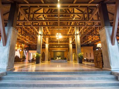 Grande réception d'hôtel ouverte avec poutres en bois apparentes et éclairage chaud.