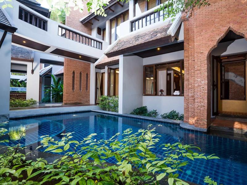 Cour intérieure d'un hôtel avec une piscine bleue et des bâtiments modernes avec balcons.