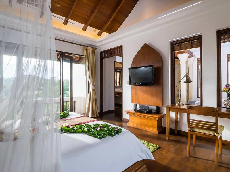 Chambre d'hôtel lumineuse avec sol en bois, TV, bureau et vue sur une terrasse.