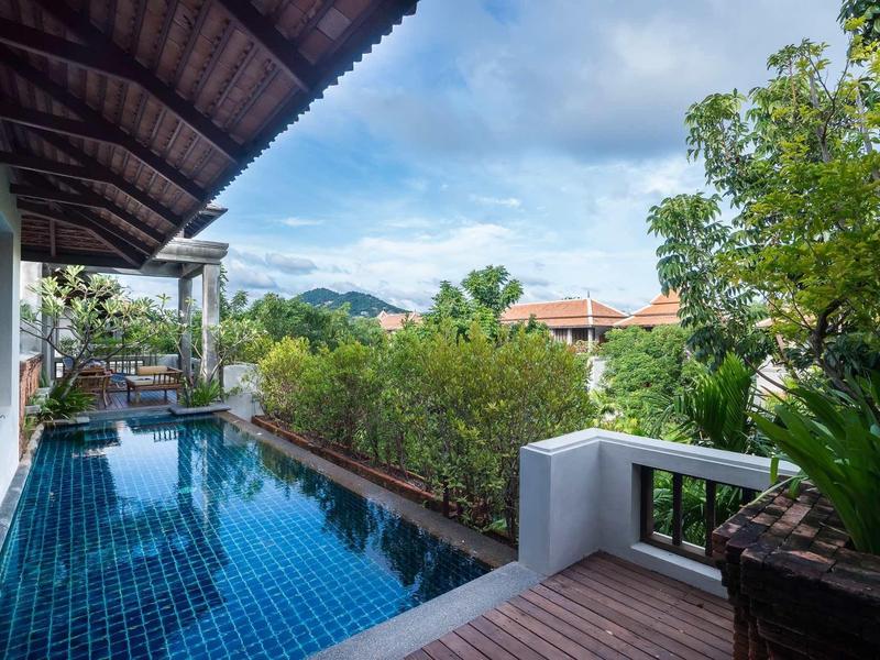 Piscine sur une terrasse d'hôtel avec végétation et vue sur la montagne.