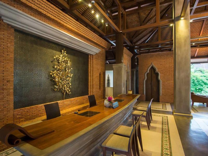 Zone de réception moderne avec comptoir en bois, chaises et mur décoratif sous un éclairage chaud.