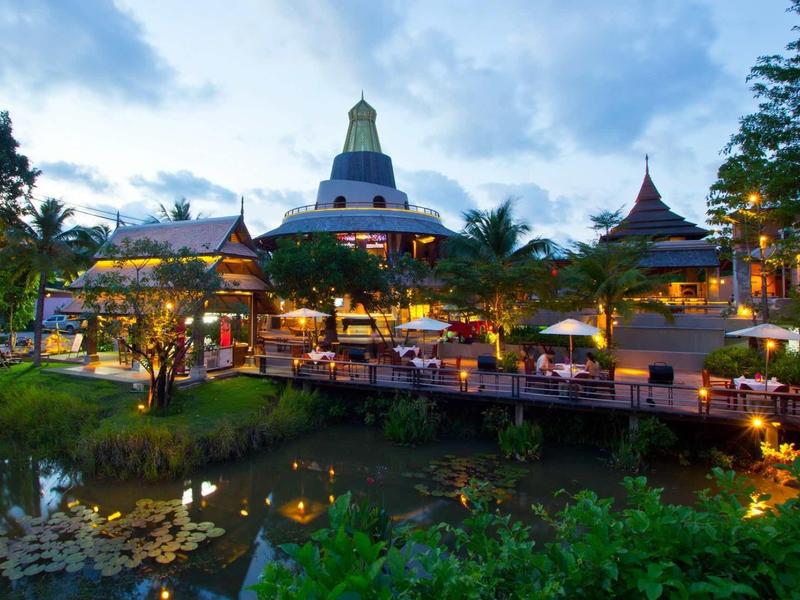 Vue du soir d'une station éclairée avec étang et architecture exotique.