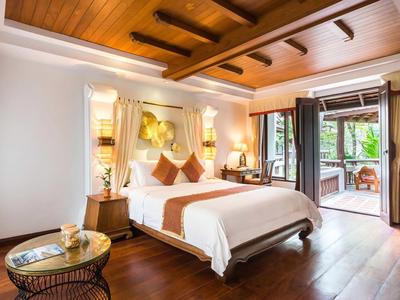 Pohodlný hotelový pokoj s dřevěnou podlahou, velkou postelí a přístupem na terasu.