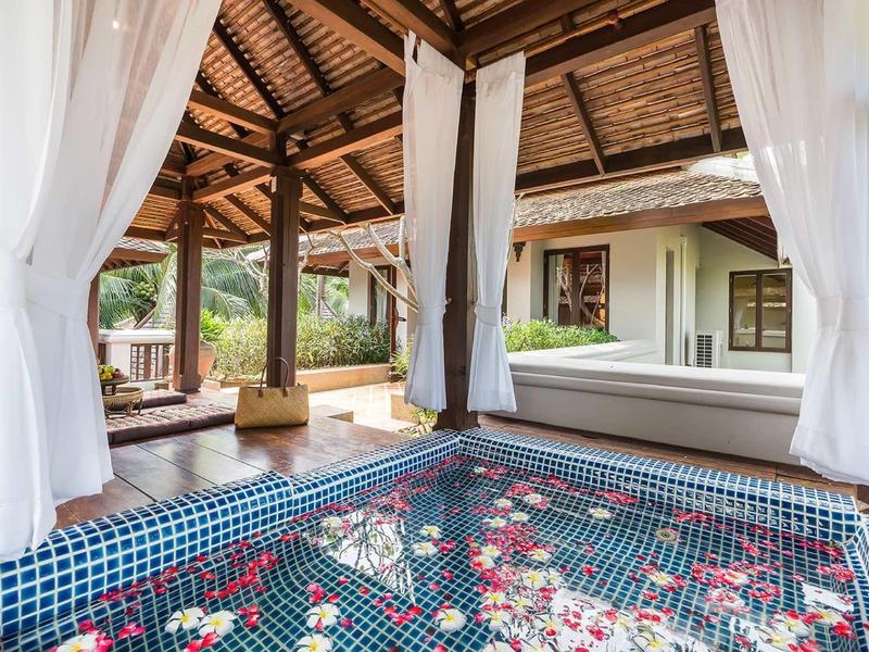 Otevřený pavilon s květinami ve vodní nádrži a výhledem na zelený venkovní prostor v resortu.