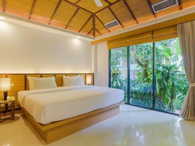 Jasny pokój hotelowy z dużym łóżkiem i widokiem na tropikalny ogród