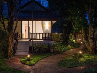 Oświetlona ścieżka w ogrodzie prowadzi do przytulnego domu wakacyjnego nocą.