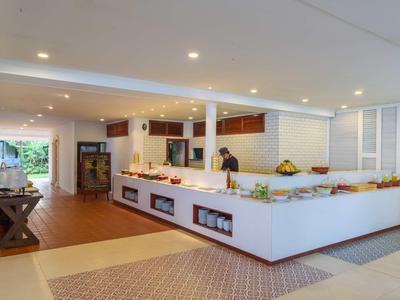 Nowoczesny bufet hotelowy z dużym białym kontuarem i różnorodnym jedzeniem.