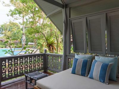 Przytulny taras z leżanką i widokiem na basen w zielonym otoczeniu.