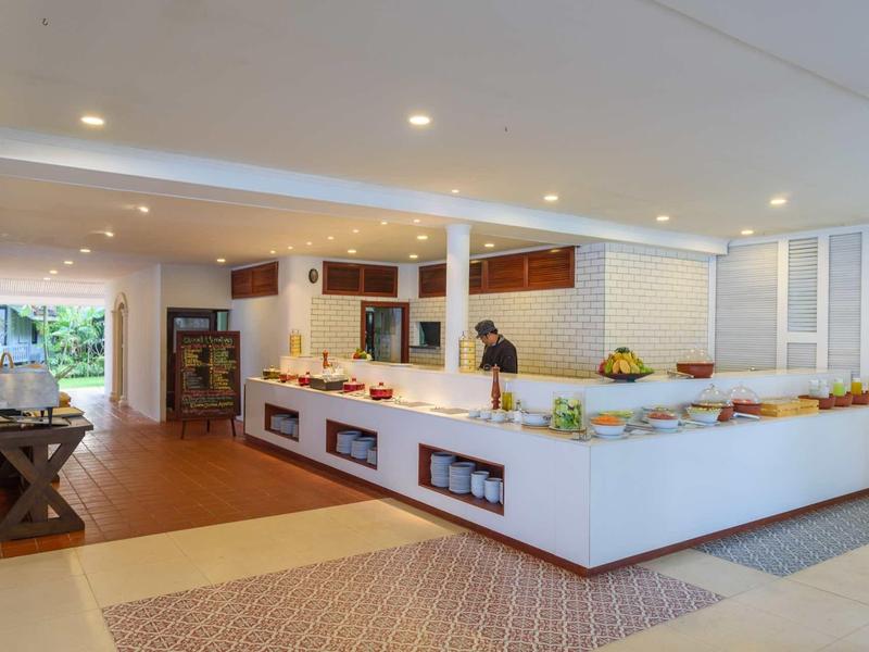 Nowoczesny bufet hotelowy z dużym białym kontuarem i różnorodnym jedzeniem.