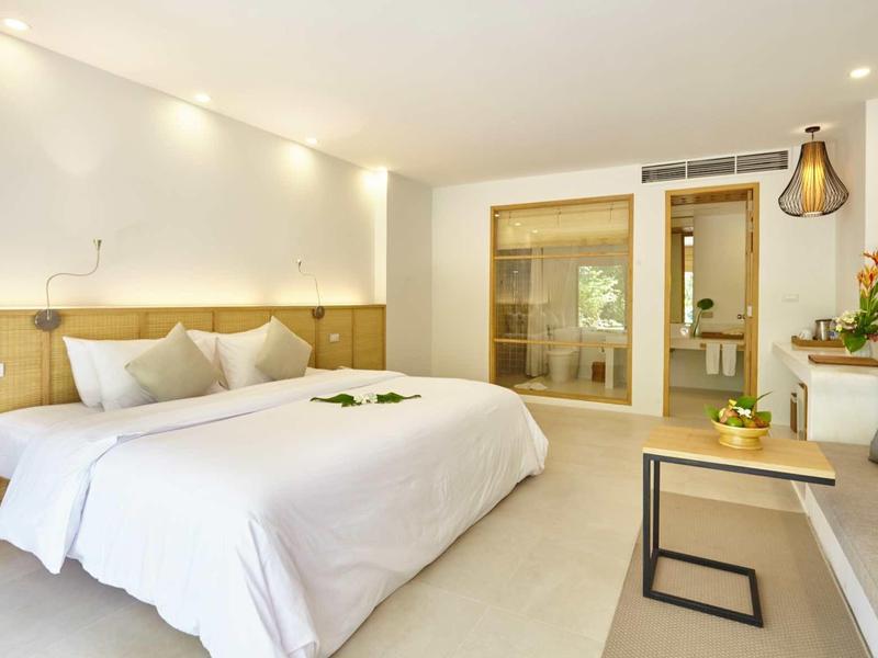 Nowoczesny pokój hotelowy z dużym łóżkiem, sofą i eleganckim oświetleniem.