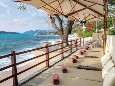 Espace détente avec transats et parasol directement sur la plage avec vue sur la mer.