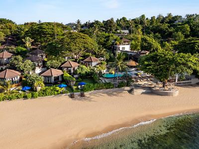Station balnéaire avec plusieurs bungalows entourés de verdure luxuriante et accès direct à la mer.