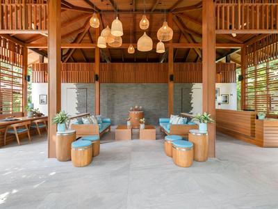 Espace lounge d'hôtel ouvert et moderne avec éléments en bois et coussins bleus