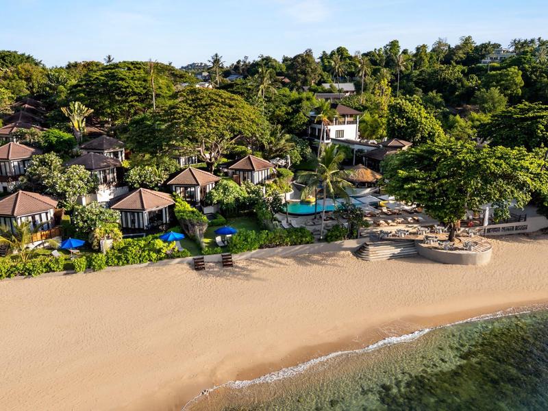 Station balnéaire avec plusieurs bungalows entourés de verdure luxuriante et accès direct à la mer.