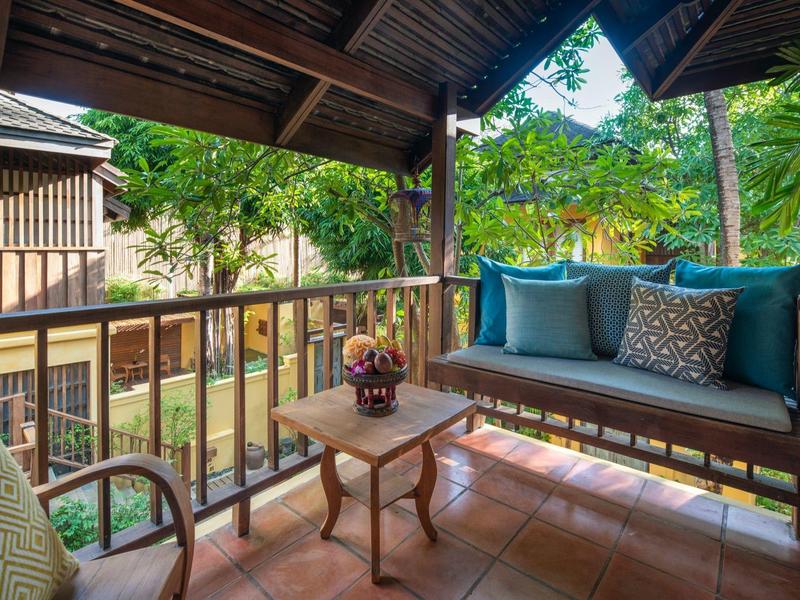 Veranda accogliente con divano, tavolo e vista su giardino tropicale