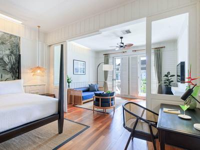 Elegantní hotelový pokoj s postelí king-size, posezením, psacím stolem a velkým oknem s výhledem na terasu.