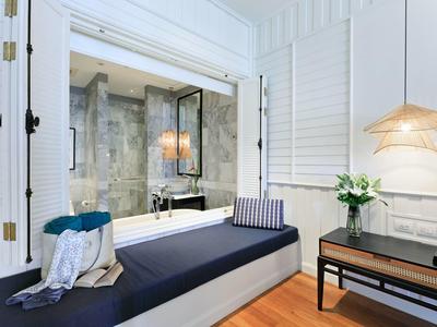 Světý pokoj s oknem do stylové koupelny a útulným posezením.