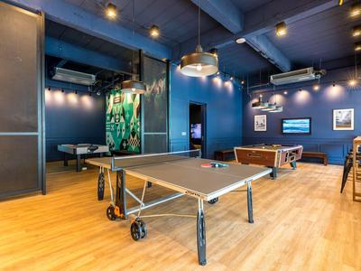 Freizeitraum mit Tischtennis- und Billardtisch, moderner Beleuchtung und Holzboden.