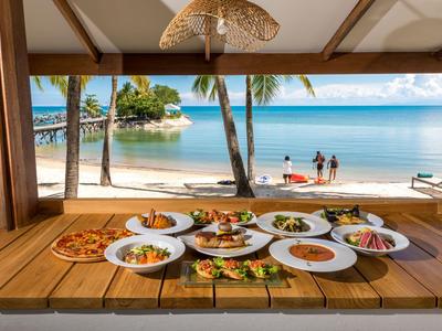 Verschiedene Gerichte auf einem Tisch mit Blick auf Strand und Meer im Hintergrund.