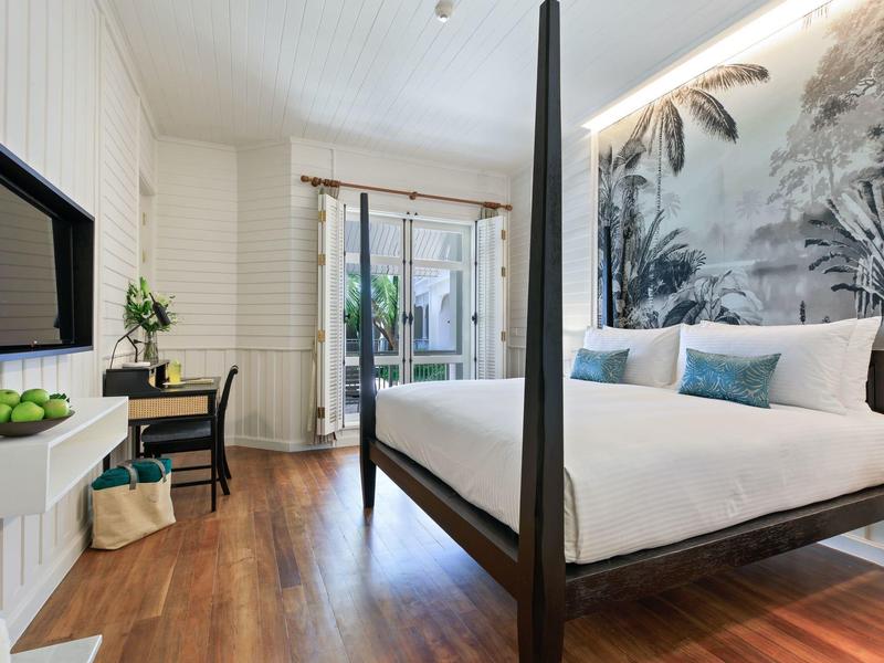 Světý moderní hotelový pokoj s dřevěnou podlahou, dvoulůžkem a přístupem na terasu.