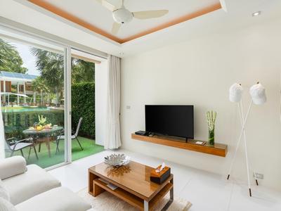 Sala moderna con sofá, TV, mesa de madera y puerta al jardín.