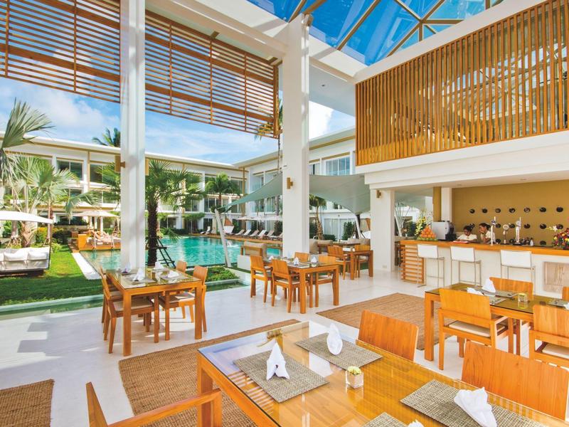 Restaurante abierto con muebles de madera con vista a una piscina a la luz del día.