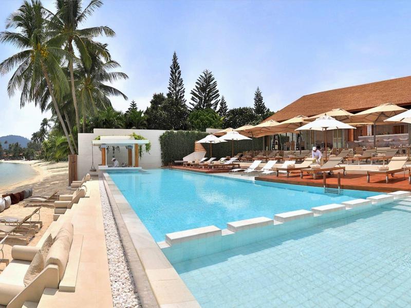 Gran piscina exterior con tumbonas y sombrillas junto a un hotel en la playa.