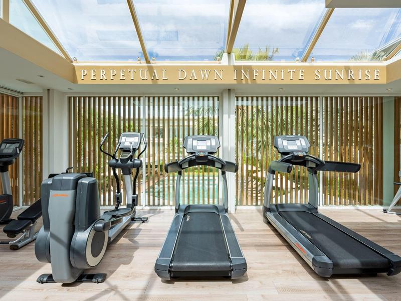 Gimnasio moderno con cintas de correr y bicicletas estáticas, sala luminosa con grandes ventanas.
