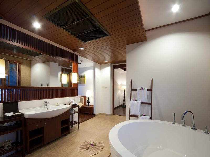 Salle de bain moderne avec grande baignoire, lavabos doubles et accents en bois.