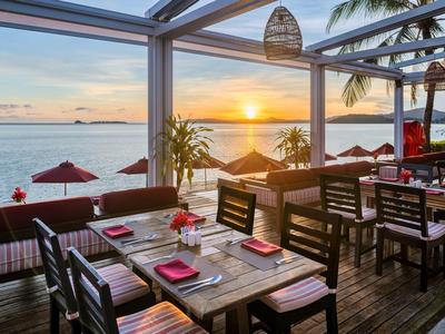 Offenes Restaurant mit Blick auf den Sonnenuntergang am Strand und Palmen