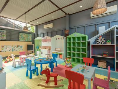 Sala de juegos colorida con muebles aptos para niños y estanterías en un hotel.