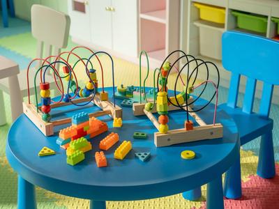 Sala de juegos infantil con juguetes coloridos sobre una mesa azul y pequeñas sillas.