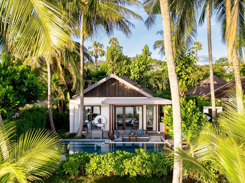 Moderner Bungalow mit Pool, umgeben von Palmen und tropischer Vegetation.