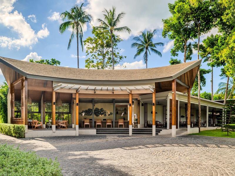 Modernes tropisches Resortgebäude mit offenem Design und umgeben von Palmen