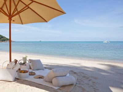 Paisaje relajante de playa con cojines y sombrilla junto al mar tranquilo.