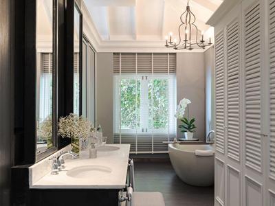 Baño moderno con bañera independiente, lavabos dobles y grandes ventanas.