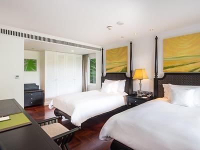 Habitación de hotel moderna con dos camas individuales, colores cálidos y suelo de madera.