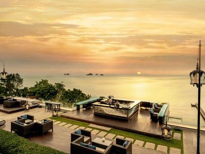 Lounge prostor s pohovkami a výhledem na moře při západu slunce u rohového hotelu.