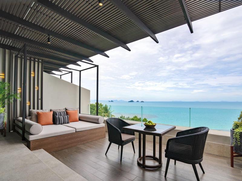 Balcón moderno con zona de estar y vistas al mar bajo un cielo nublado.