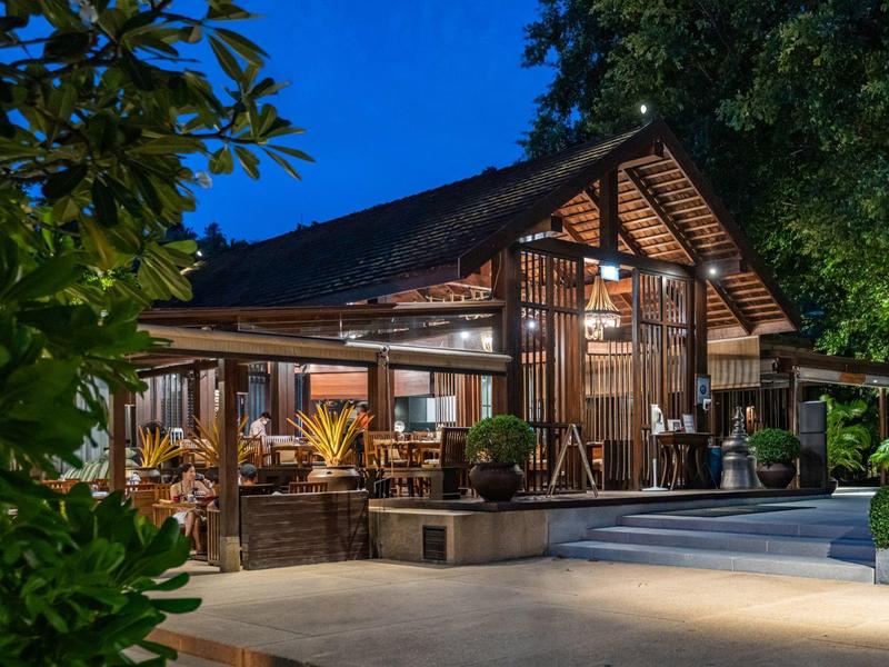 Casa de madera iluminada rodeada de árboles en una noche despejada.